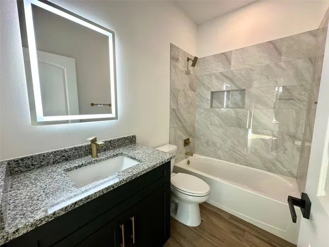 a bathroom with a granite countertop sink toilet a mirror and shower