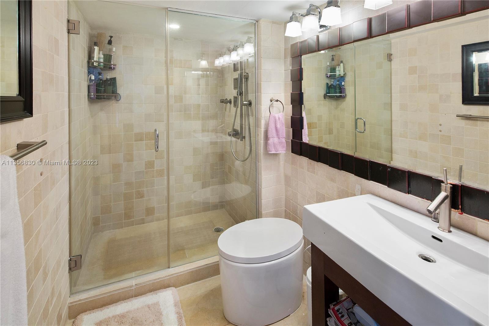 90 Alton Road, Unit 2906 Miami Beach, FL 33139 - Photo 4 of 6 a bathroom with a sink a toilet a mirror and shower