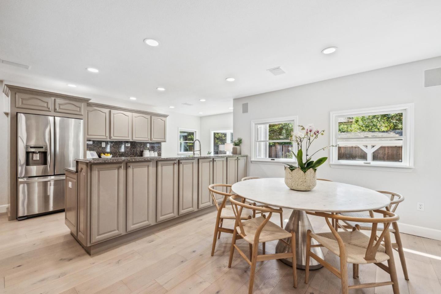 961 Berkeley Avenue Menlo Park, CA 94025 - Photo 11 of 27 a kitchen with stainless steel appliances granite countertop a dining table chairs refrigerator and microwave