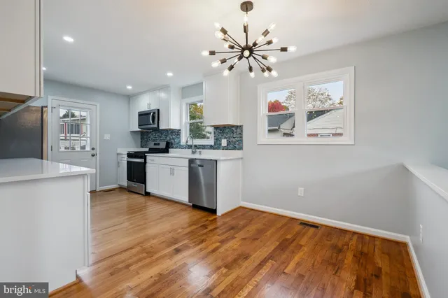 a kitchen with stainless steel appliances a white cabinets wooden floor and a sink