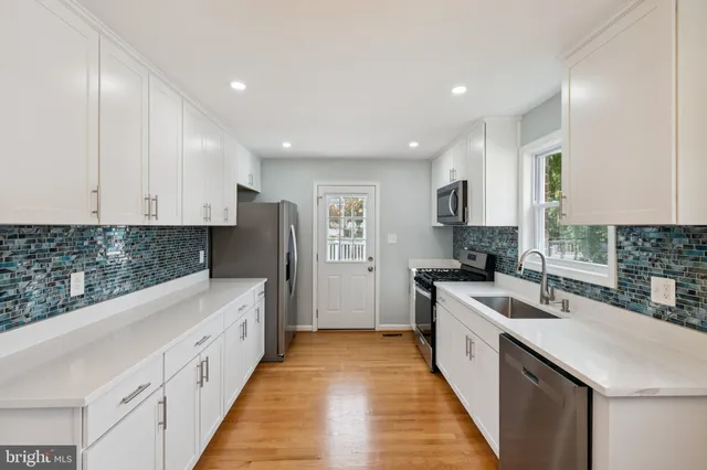 a kitchen with white cabinets sink and stove