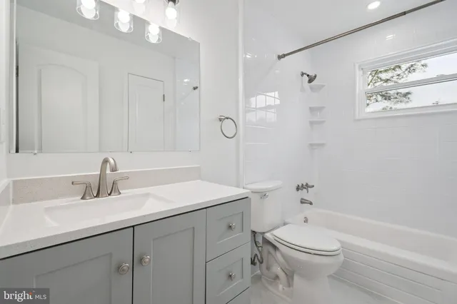 a bathroom with a toilet a sink a mirror a shower a vanity and window