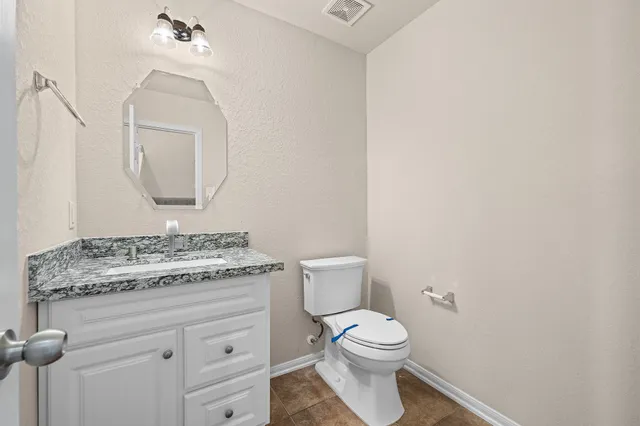 a bathroom with a granite countertop toilet sink and mirror