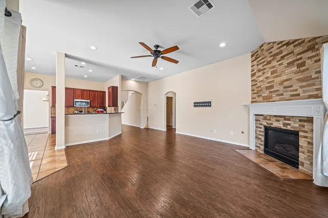 a view of a kitchen and an empty room with wooden floor