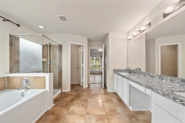 a spacious bathroom with a granite countertop tub sink shower and mirror