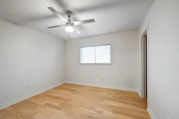 an empty room with a window and a fan