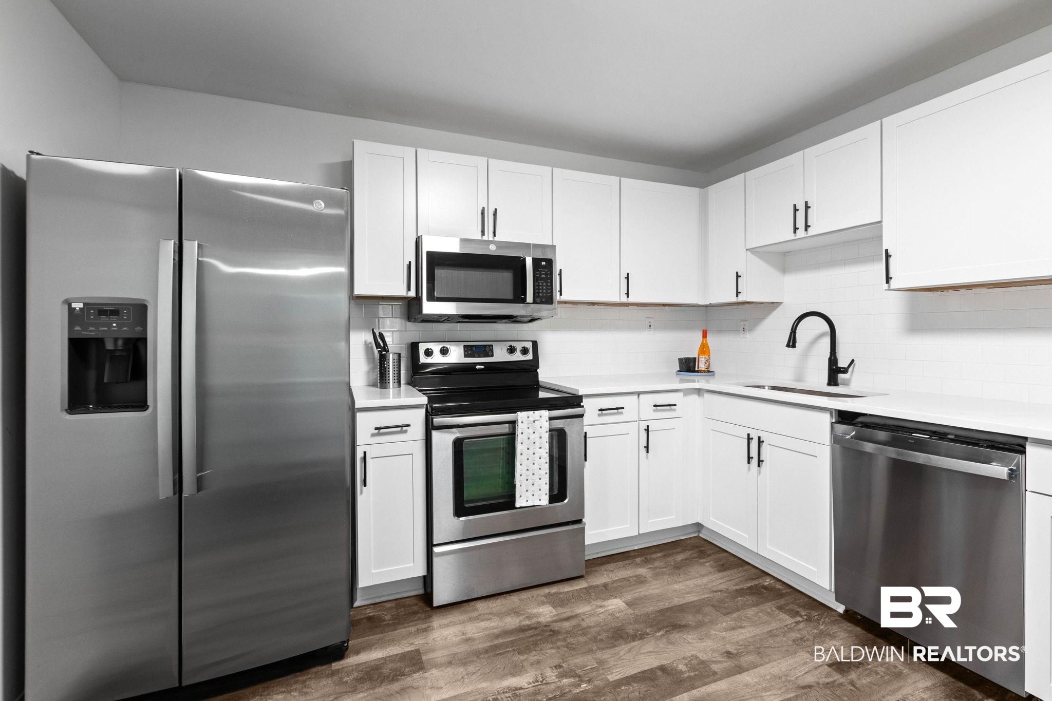 128 Bush Avenue Mobile, AL 36604 - Photo 10 of 40 Kitchen featuring stainless steel appliances, white cabinets, dark wood finished floors, and backsplash