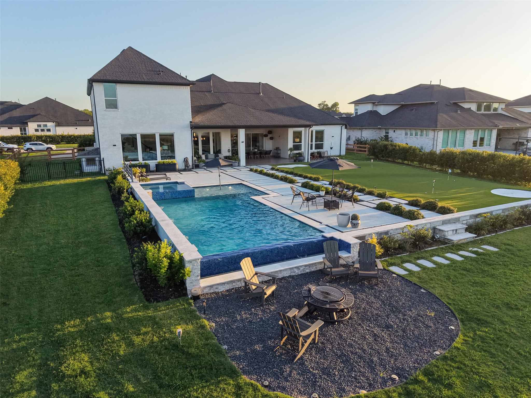 29612 Fulshear Lake Trace Fulshear, TX 77406 - Photo 8 of 48 This spacious backyard features a modern home with a luxurious swimming pool, a cozy fire pit area, and well-maintained landscaping, perfect for outdoor relaxation and entertainment.