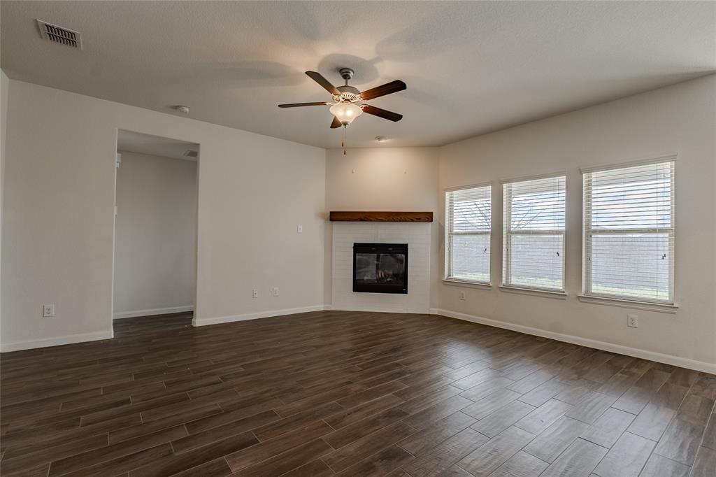 240 Copper Switch Drive Anna, TX 75409 - Photo 16 of 33 Unfurnished living room with dark wood-type flooring, a ceiling fan, and a tile fireplace