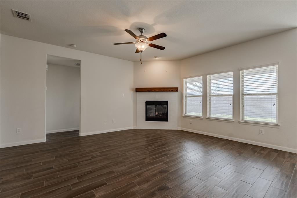240 Copper Switch Drive Anna, TX 75409 - Photo 17 of 33 Unfurnished living room with dark wood finished floors, a ceiling fan, and a glass covered fireplace