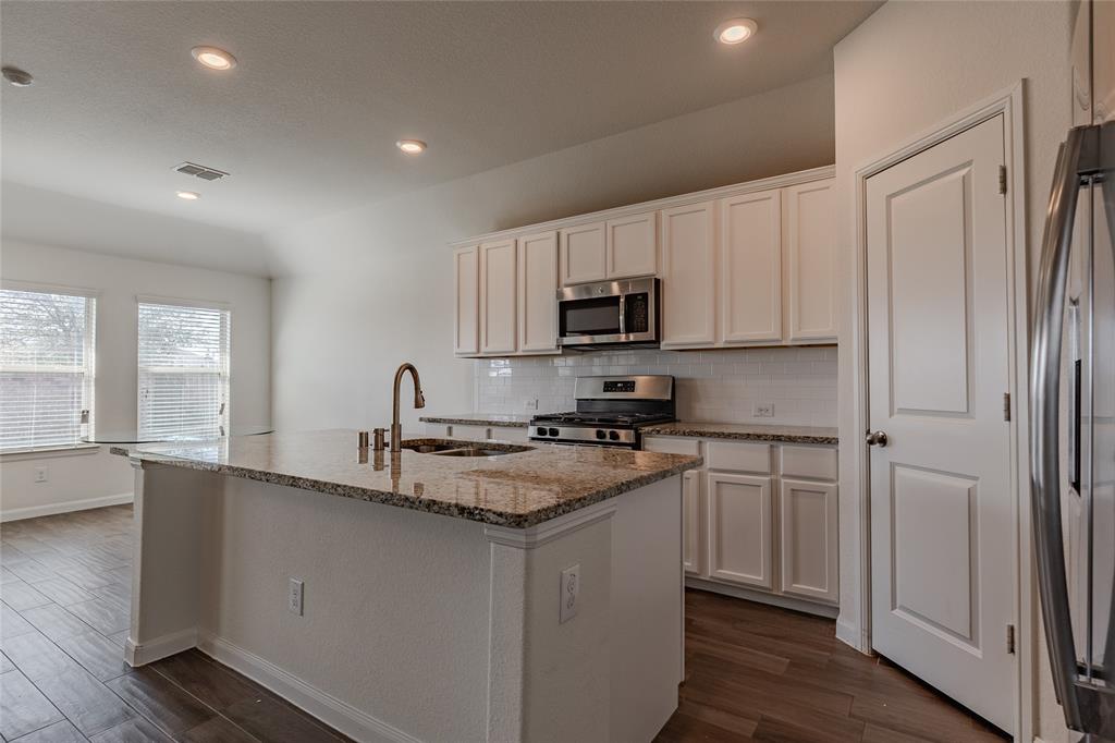 240 Copper Switch Drive Anna, TX 75409 - Photo 21 of 33 Kitchen with dark wood-style flooring, light stone counters, stainless steel appliances, decorative backsplash, and recessed lighting