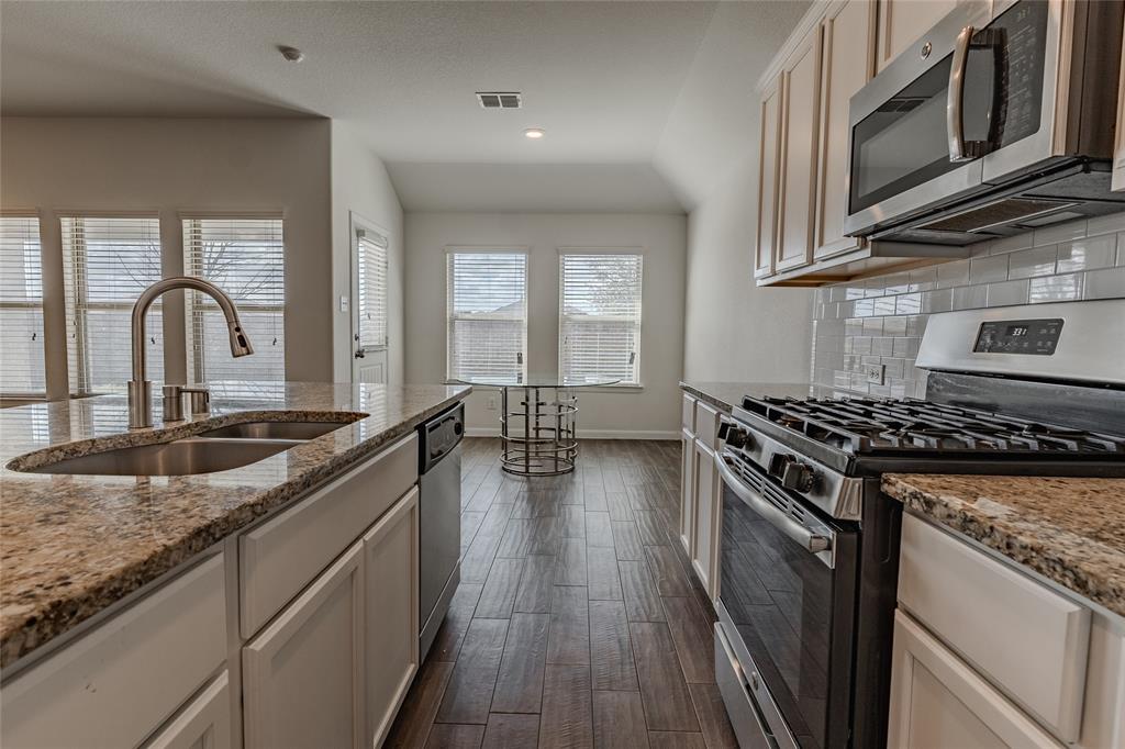 240 Copper Switch Drive Anna, TX 75409 - Photo 22 of 33 Kitchen featuring appliances with stainless steel finishes, dark wood finished floors, decorative backsplash, light stone countertops, and recessed lighting