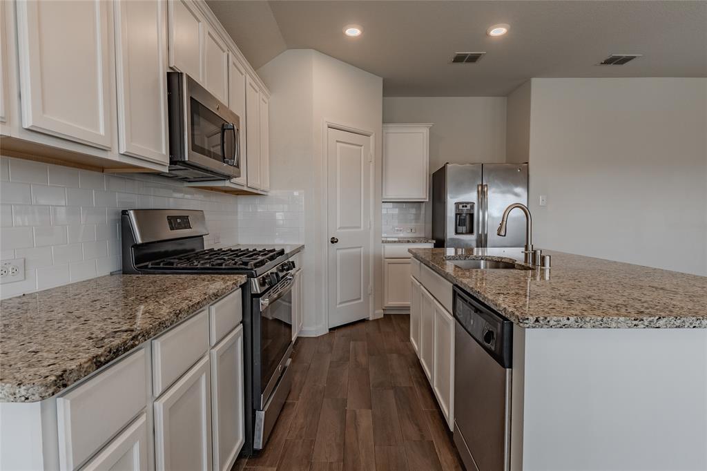 240 Copper Switch Drive Anna, TX 75409 - Photo 23 of 33 Kitchen with appliances with stainless steel finishes, dark wood-style floors, a kitchen island with sink, white cabinetry, and light stone countertops