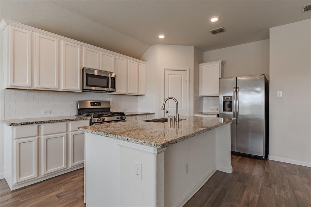 240 Copper Switch Drive Anna, TX 75409 - Photo 24 of 33 Kitchen featuring stainless steel appliances, dark wood finished floors, white cabinetry, decorative backsplash, and light stone countertops