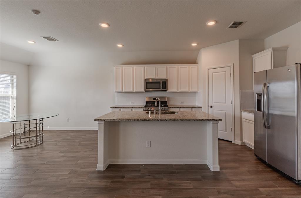 240 Copper Switch Drive Anna, TX 75409 - Photo 10 of 33 Kitchen with stainless steel appliances, dark wood finished floors, light stone countertops, a kitchen island with sink, and recessed lighting