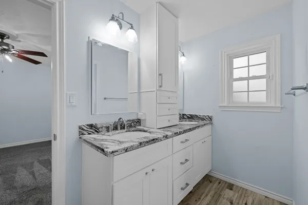 an empty room with wooden floor fan and windows