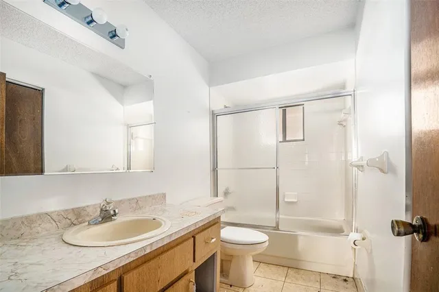 a bathroom with a granite countertop sink toilet mirror and shower