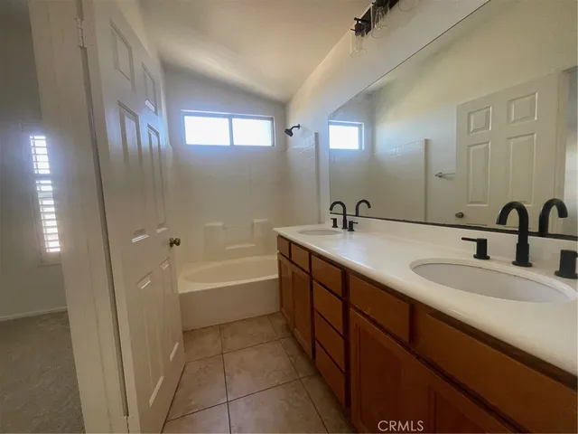 a bathroom with a double vanity sink a mirror and a bathtub