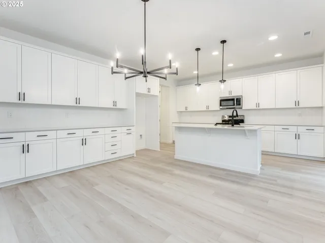 a large kitchen with white cabinets and stainless steel appliances