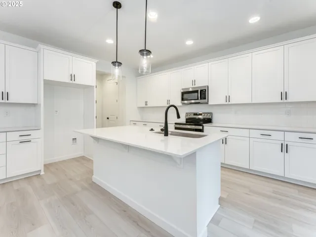 a kitchen with kitchen island a sink stainless steel appliances and cabinets