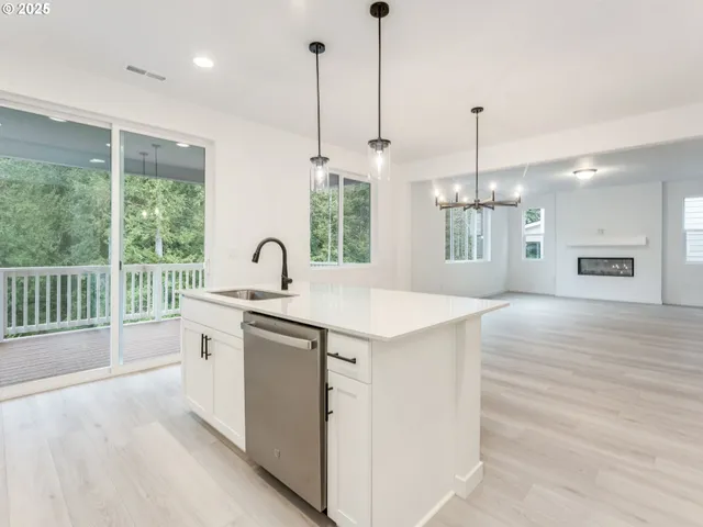 a kitchen with stainless steel appliances granite countertop a sink a window and a wooden floor