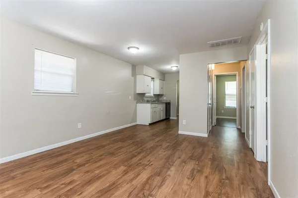 a view of a big room with wooden floor and windows