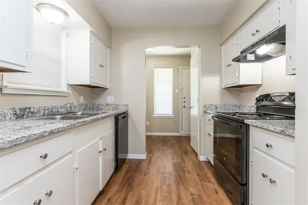 a kitchen with granite countertop cabinets stainless steel appliances and a wooden floor