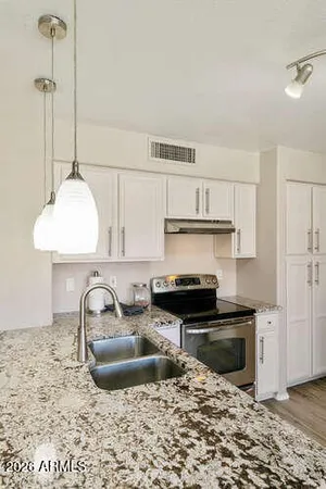 a kitchen with kitchen island granite countertop a sink stainless steel appliances and cabinets