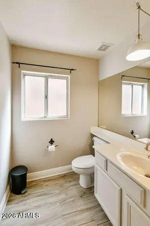 a bathroom with a granite countertop sink toilet a mirror and a window