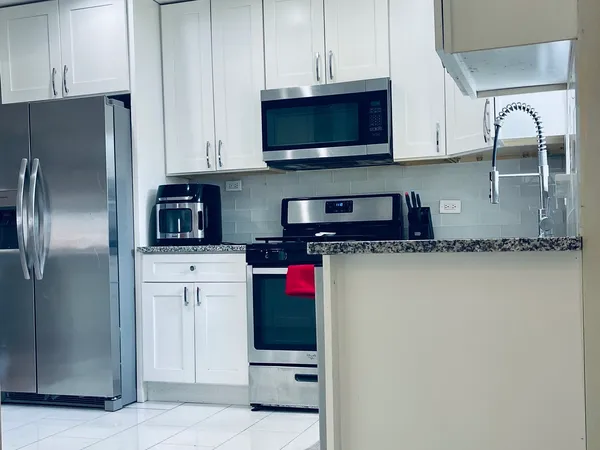 a kitchen with stainless steel appliances granite countertop a refrigerator a stove top oven and sink