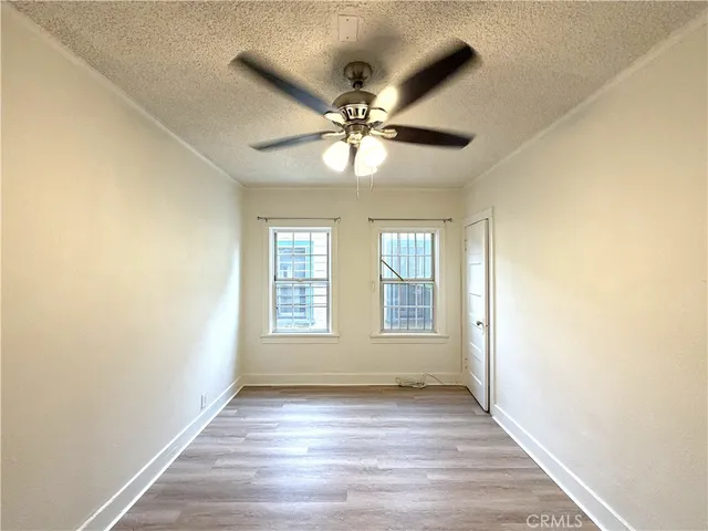 a view of an empty room with window and chandelier fan