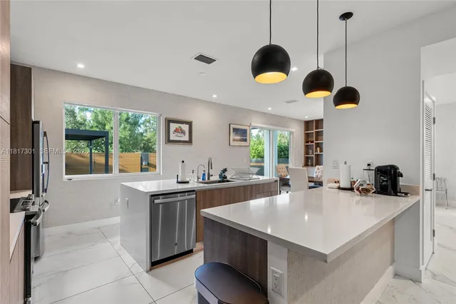 a kitchen with a stove a refrigerator a sink a dining table and chairs with wooden floor