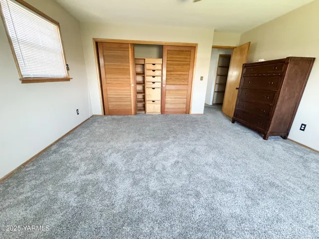 a view of an empty room with closet and a window
