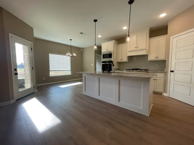 a kitchen with stainless steel appliances granite countertop a sink a stove a refrigerator and a wooden floor