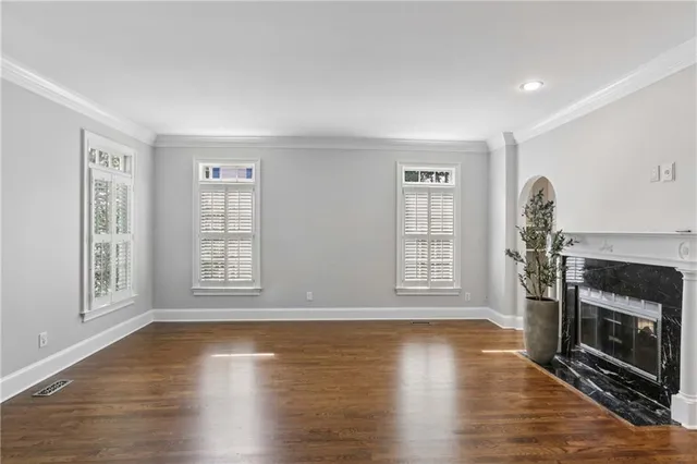 a view of an empty room with wooden floor fireplace and a window
