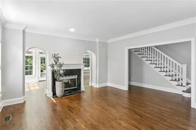 a view of an empty room with wooden floor fireplace and a window