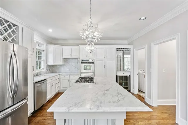 a kitchen with stainless steel appliances granite countertop a refrigerator oven a sink dishwasher and white cabinets with wooden floor