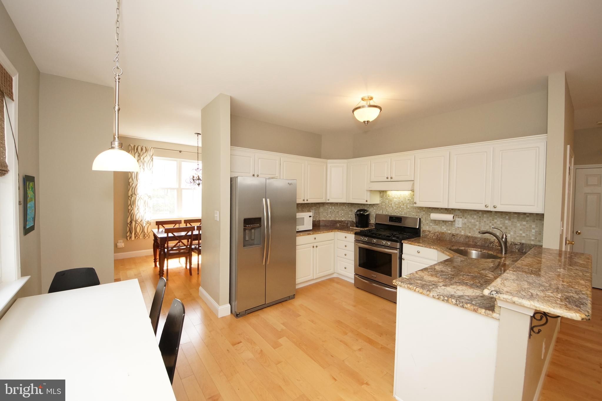66 Manley Road Pennington, NJ 08534 - Photo 22 of 60 a kitchen with stainless steel appliances kitchen island granite countertop a refrigerator a stove a sink a dining table and chairs with wooden floor