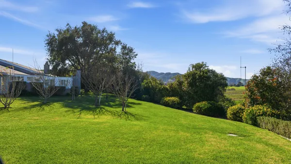 an aerial view of residential houses with outdoor space and trees