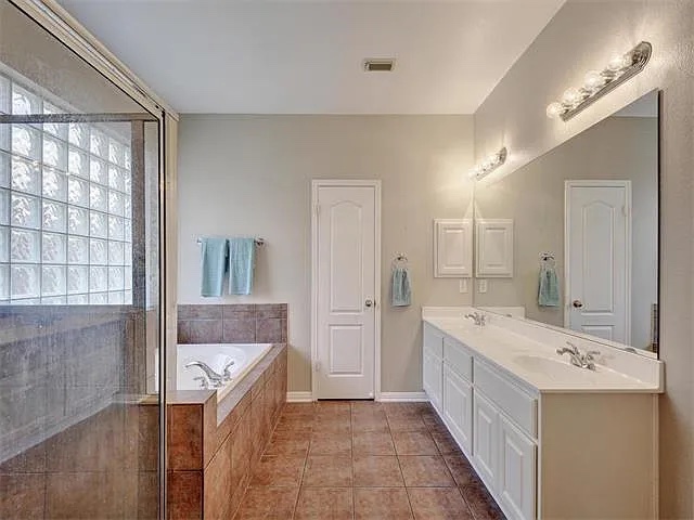1832 Nelson Ranch Loop Cedar Park, TX 78613 - Photo 9 of 15 Tiled flooring complements a dual vanity and a deep soaking tub in this primary bathroom.