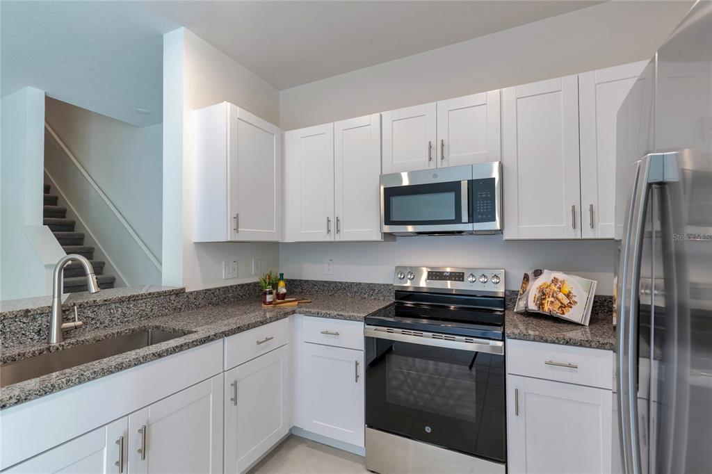 11091 Wishing Cloud Road Land O Lakes, FL 34638 - Photo 9 of 25 a kitchen with stainless steel appliances granite countertop white cabinets a stove a sink and dishwasher