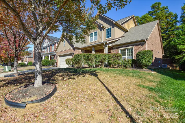 a view of a white house next to a yard with plants and trees