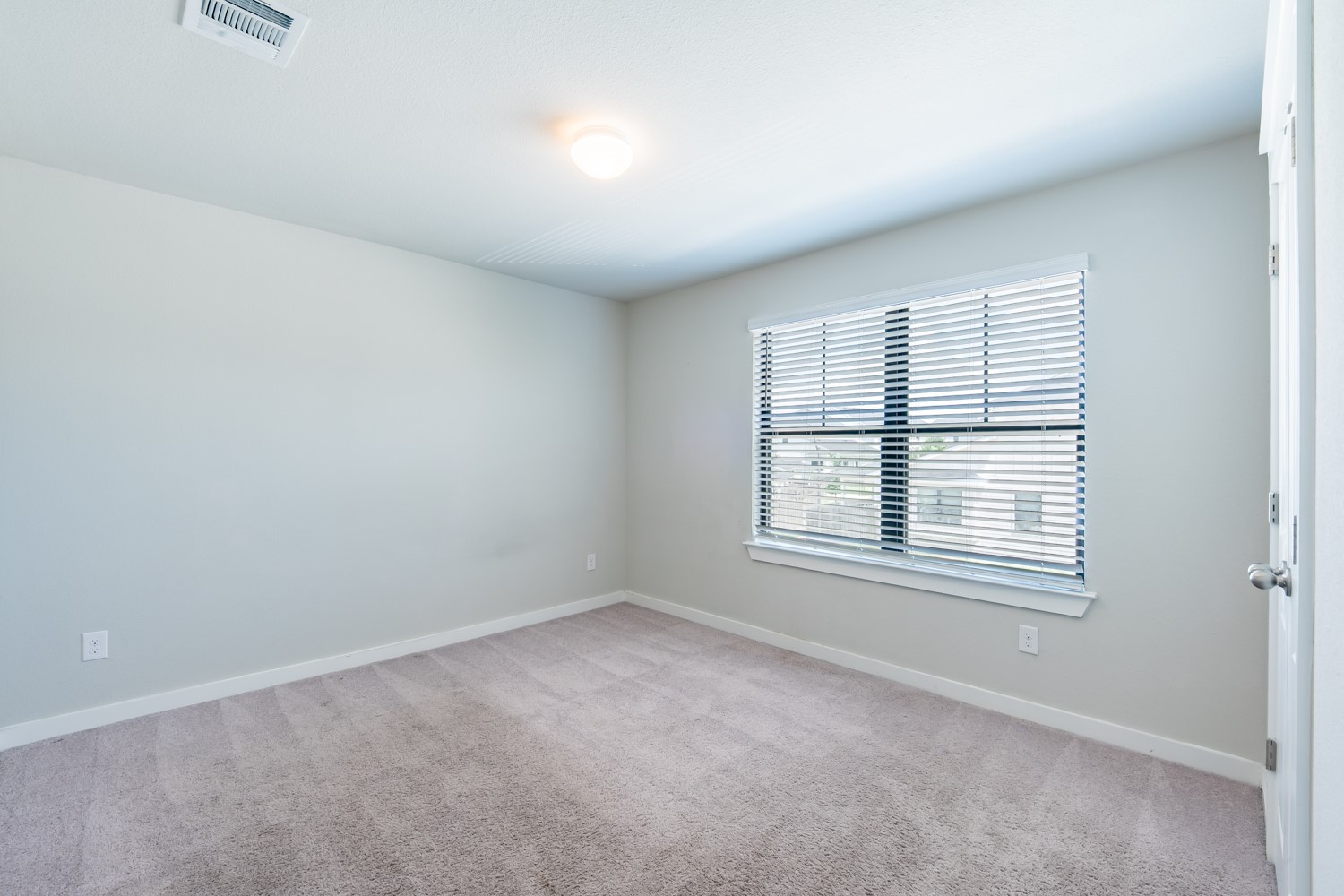 147 Waterside Road, Unit A Buda, TX 78610 - Photo 22 of 27 A spacious and inviting bedroom with soft carpet, offering tranquil views through a wide window.