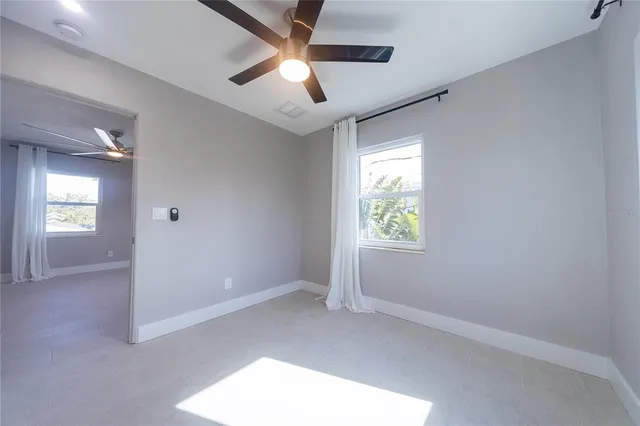 an empty room with windows and ceiling fan