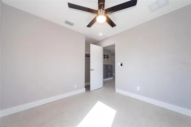 an empty room with closet and a ceiling fan