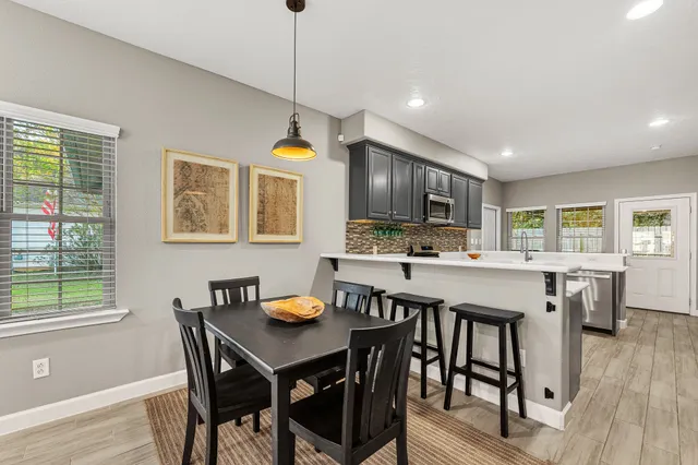 a kitchen with stainless steel appliances granite countertop a stove a refrigerator a kitchen island a dining table and chairs with wooden floor