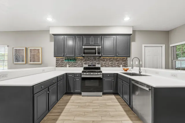 a kitchen with stainless steel appliances granite countertop a sink stove and cabinets