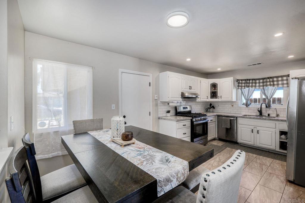 924 Daisy Street Escondido, CA 92027 - Photo 3 of 25 a large kitchen with kitchen island white cabinets and refrigerator stove