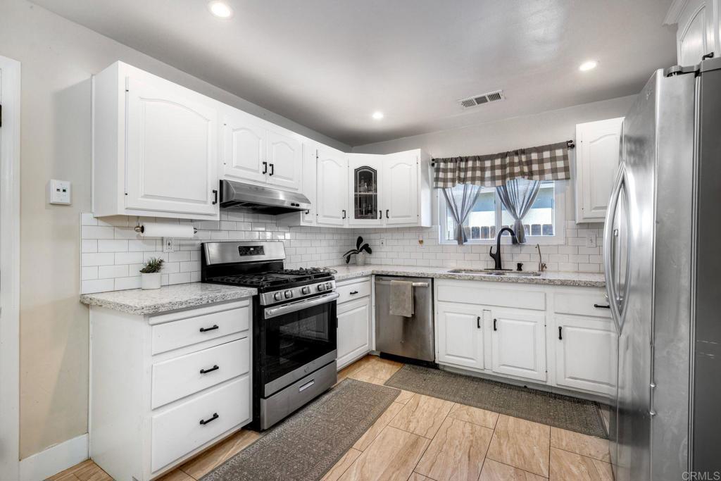 924 Daisy Street Escondido, CA 92027 - Photo 4 of 25 a kitchen with stainless steel appliances granite countertop a sink a stove a refrigerator and white cabinets