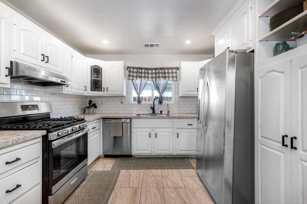 924 Daisy Street Escondido, CA 92027 - Photo 5 of 25 a kitchen with stainless steel appliances granite countertop a stove a sink and a refrigerator